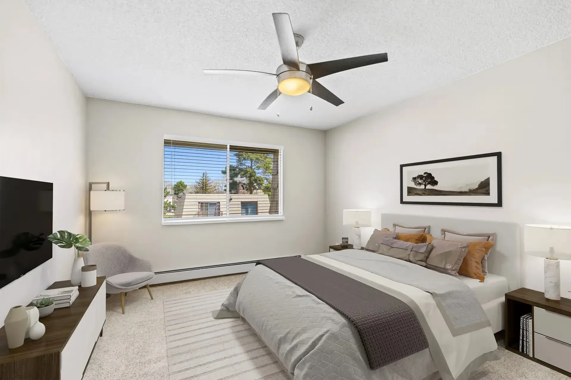 Bedroom in a modern apartment with a bed, two nightstands, lamps, ceiling fan, and a window at Avec Greeley.
