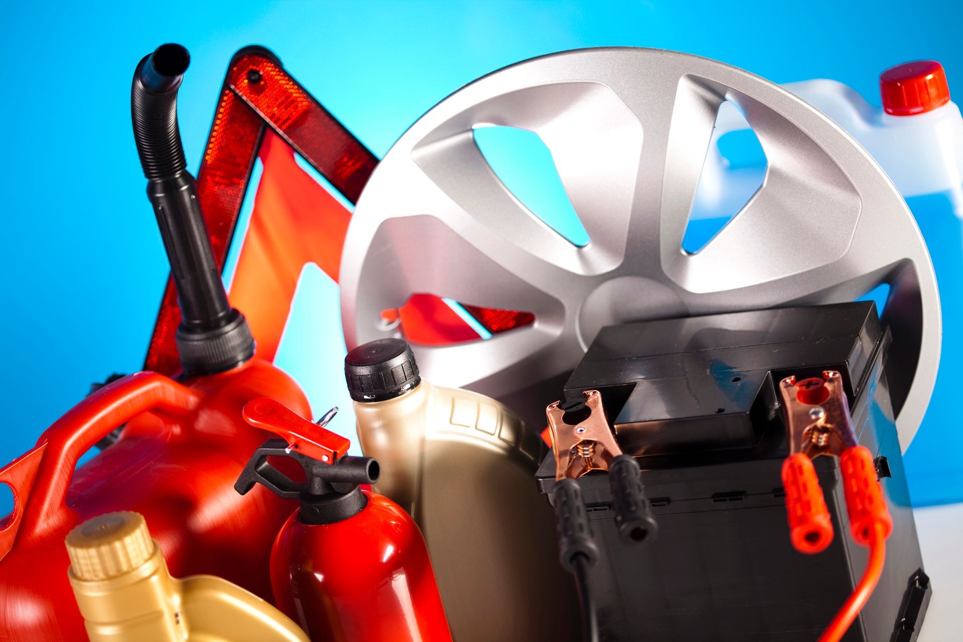 Articoli per la manutenzione dell'auto: tanica di benzina, liquido refrigerante, olio, batteria, ruota e triangolo di sicurezza su sfondo blu.