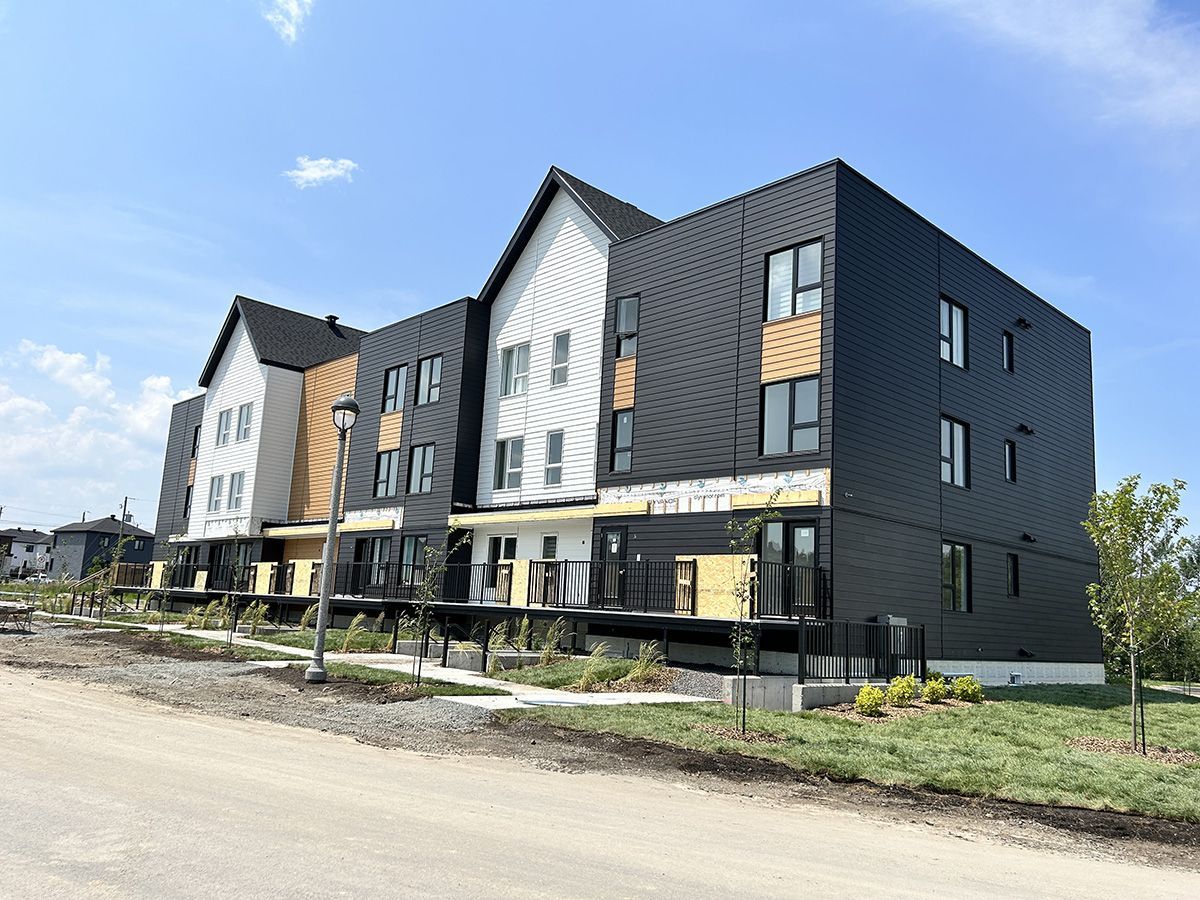 Maisons de ville modernes aux façades noires et blanches sous un ciel bleu.