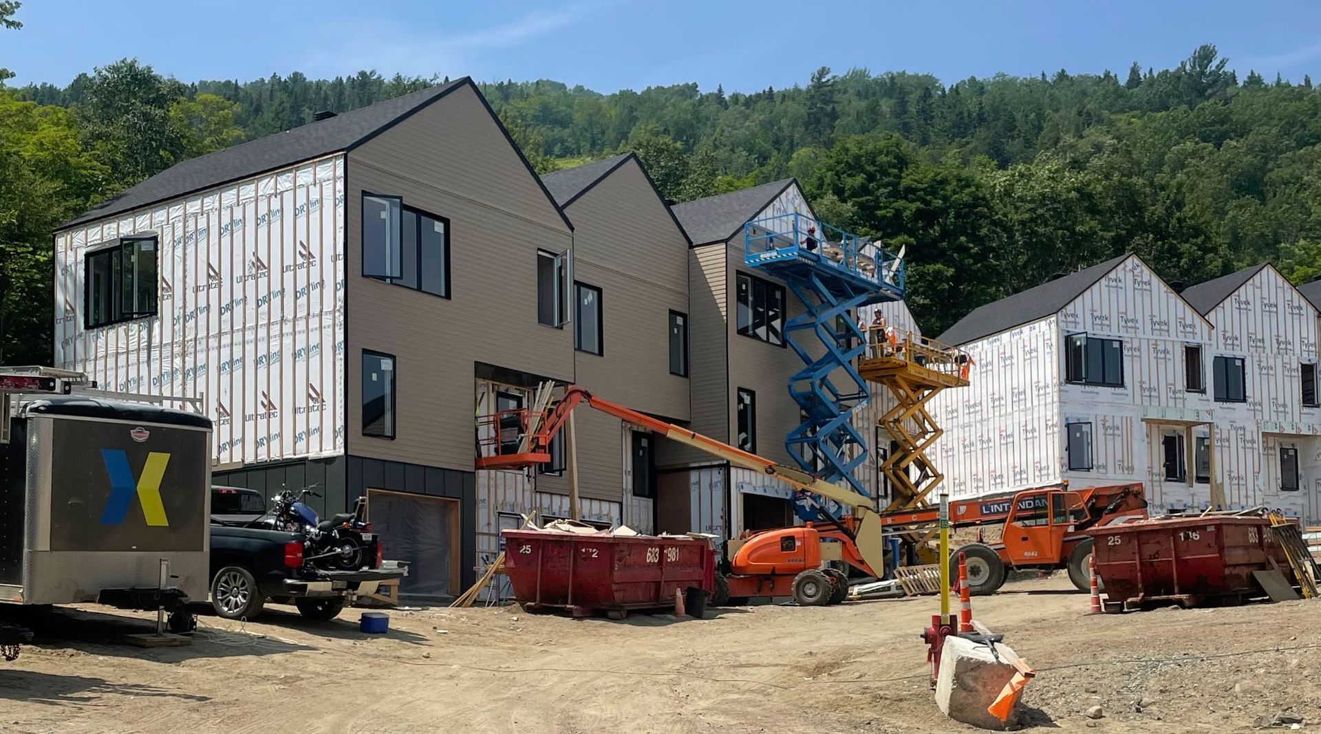 Chantier de construction de maisons de ville. Présence de grues et de bennes à gravats.