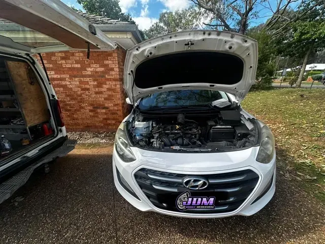White Hyundai car with open hood, parked in front of a brick building. — JDM Mobile Mechanical in Fairfield, NSW