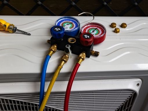 Gauges with blue, yellow, and red hoses connected to an HVAC unit.