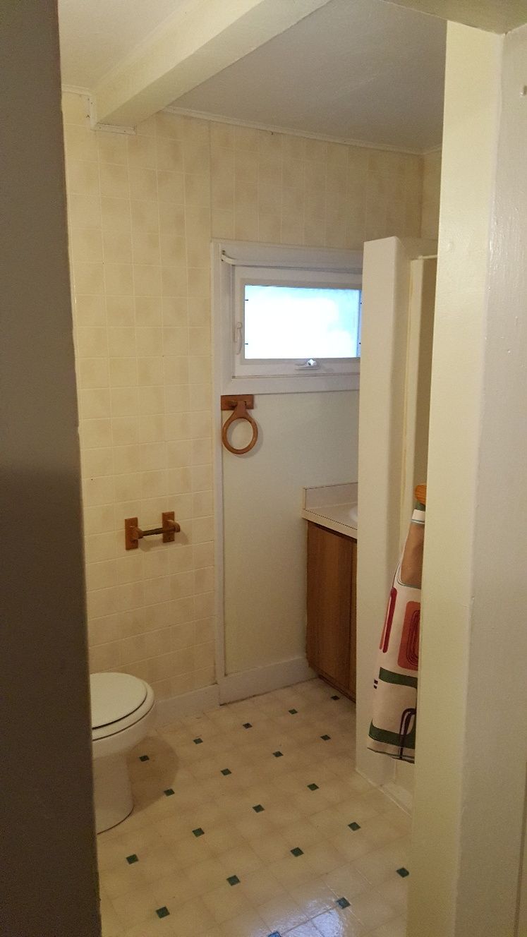 Small bathroom with beige tile, toilet, sink, and shower stall. Window over the sink.