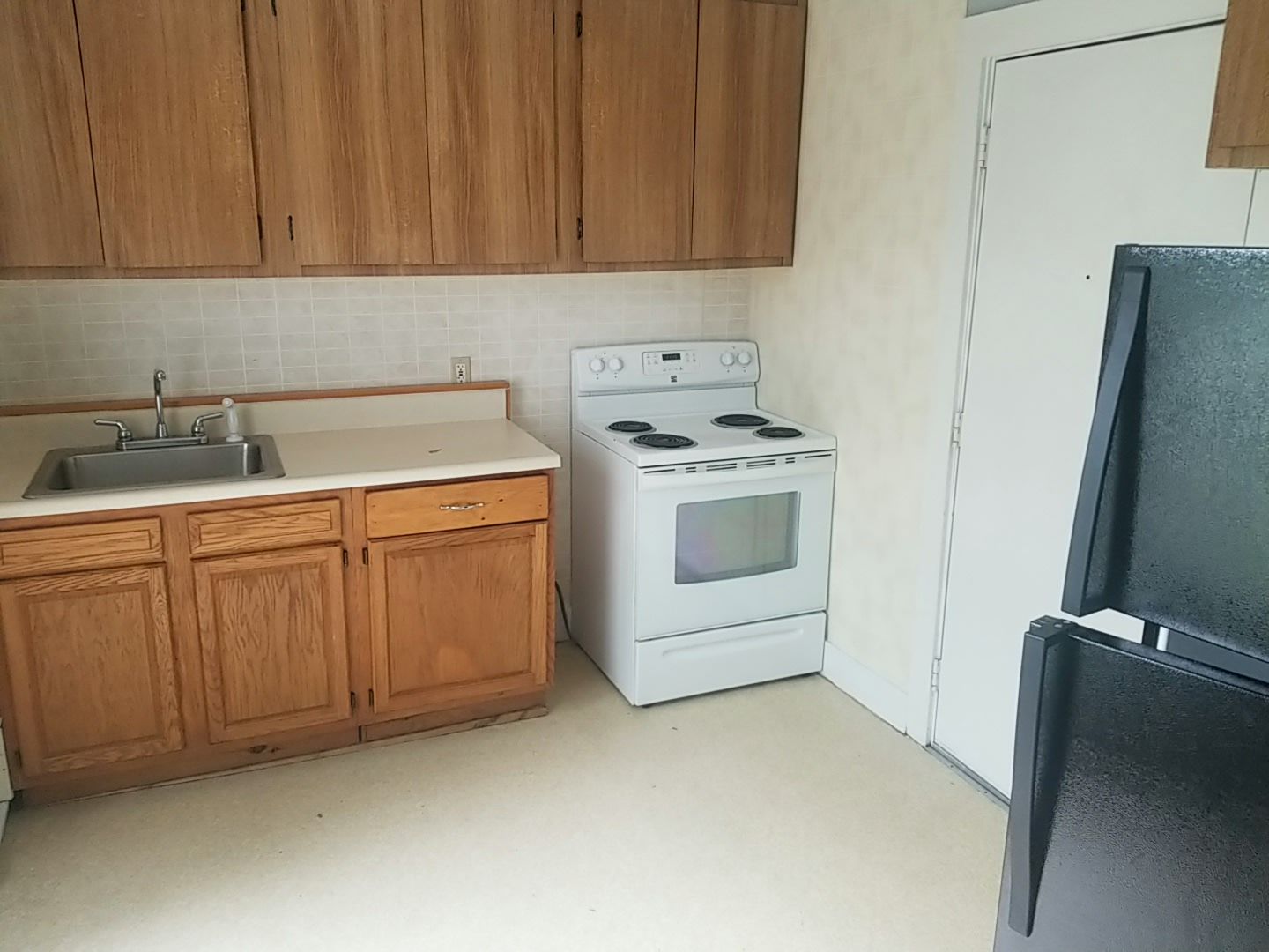 Kitchen with wooden cabinets, white stove, and black refrigerator.
