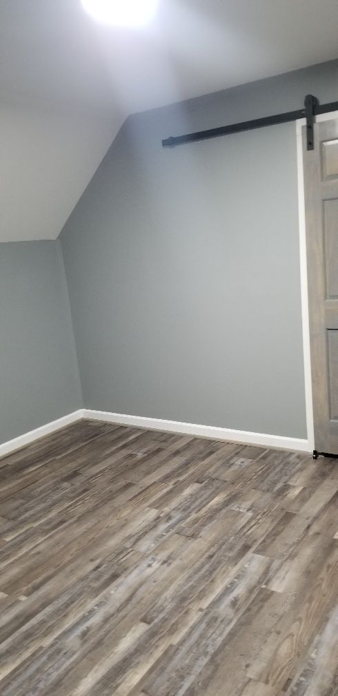 Empty room with gray walls, wood-look flooring, and a sliding door.