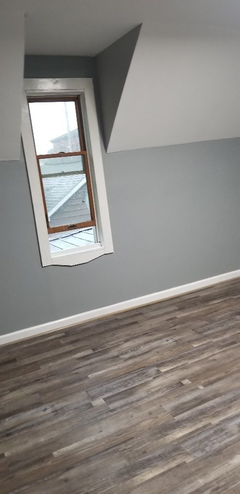 Interior room with gray walls, angled window, and wood-look flooring.