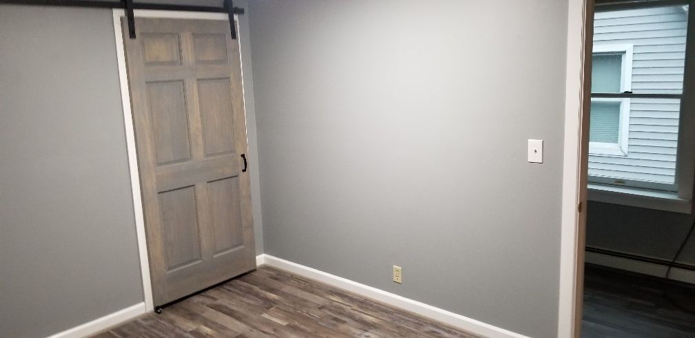 A gray room with a sliding barn door and a window.
