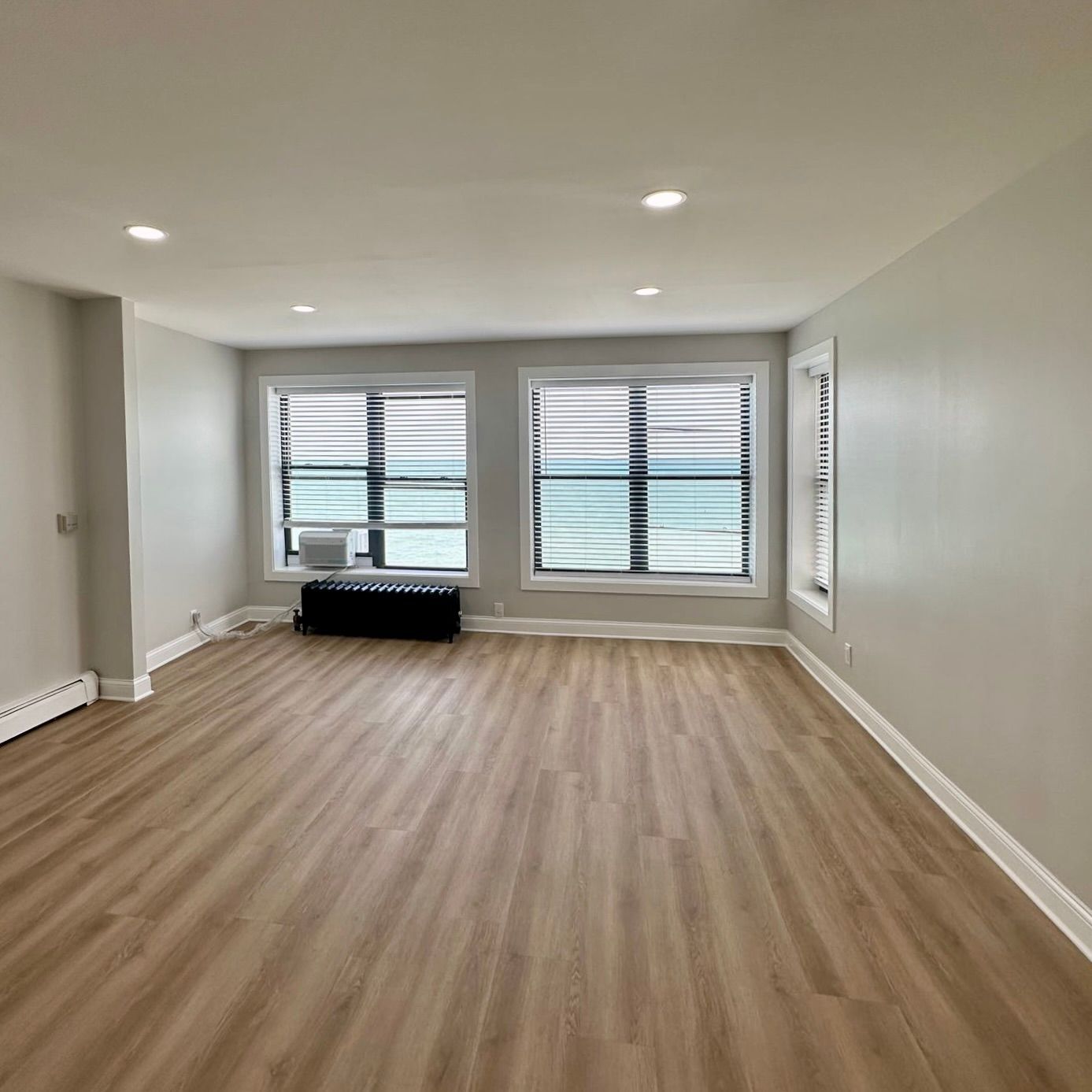 Interior living room with 3 tall windows and hardwood floors