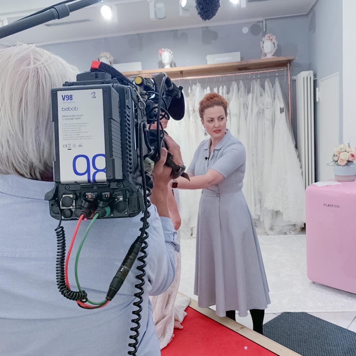 Eine Frau steht vor einer Kamera mit der Nummer 98 darauf