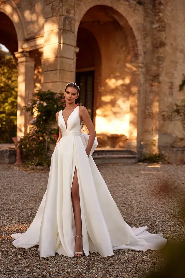 Eine Frau in einem weißen Brautkleid steht vor einem Gebäude.