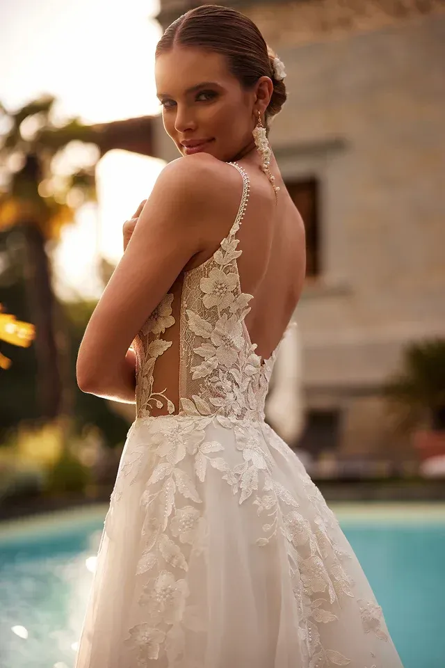 Eine Frau in einem Brautkleid steht neben einem Pool.