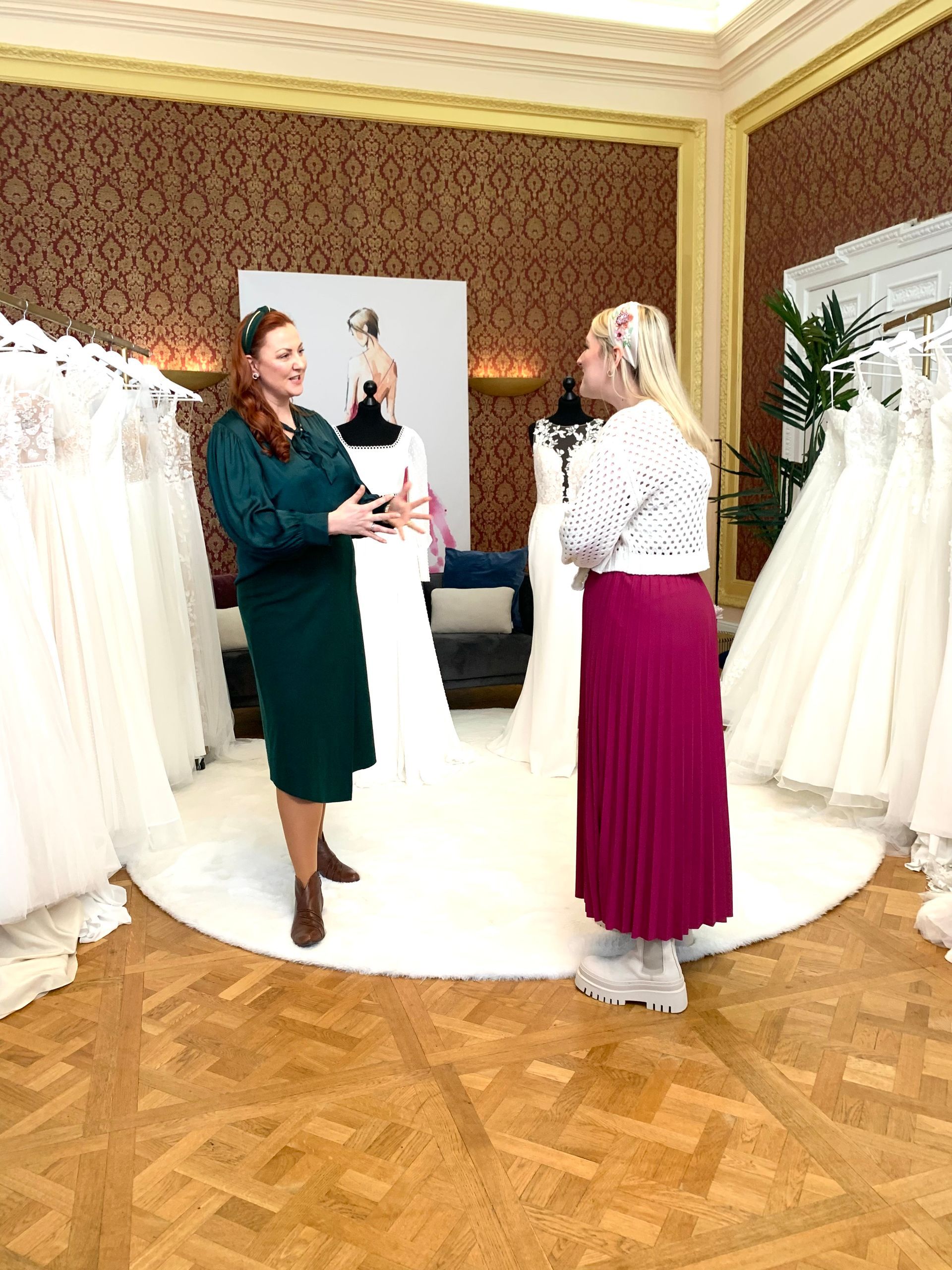 Zwei Frauen stehen in einem Raum mit vielen Brautkleidern.