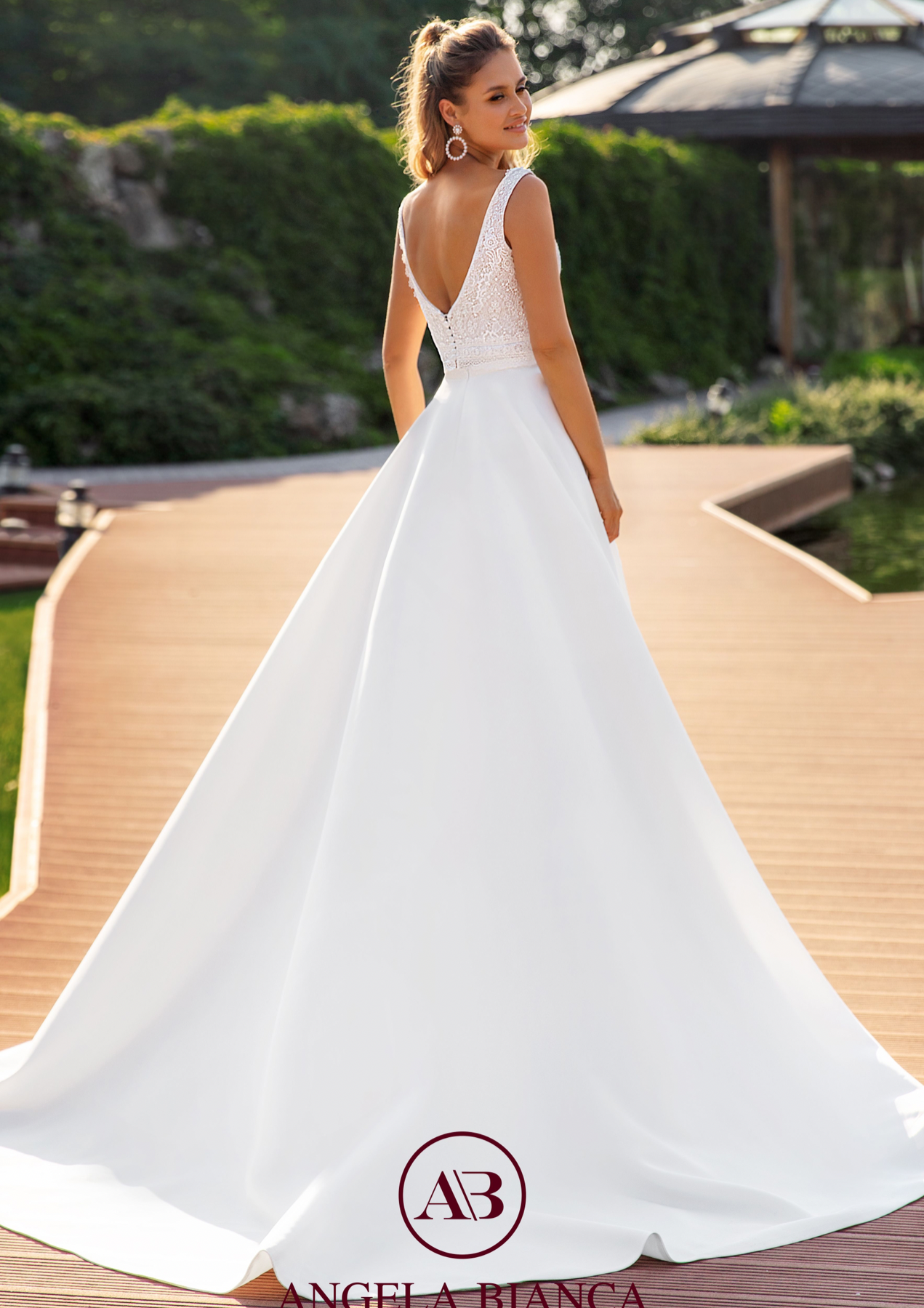 Eine Frau in einem weißen Brautkleid steht auf einem Holzsteg.