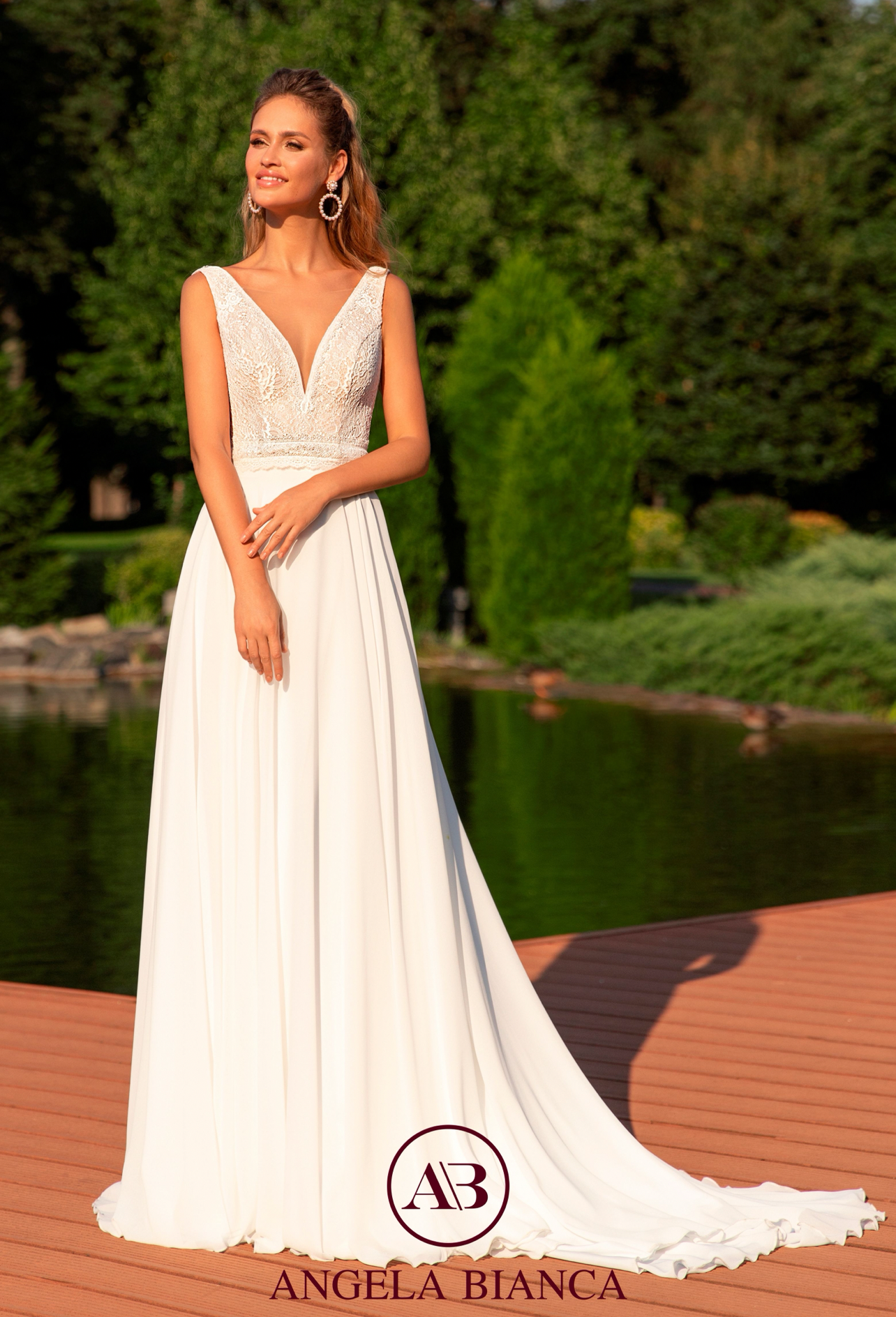 Eine Frau in einem weißen Brautkleid steht auf einem Holzsteg neben einem See.