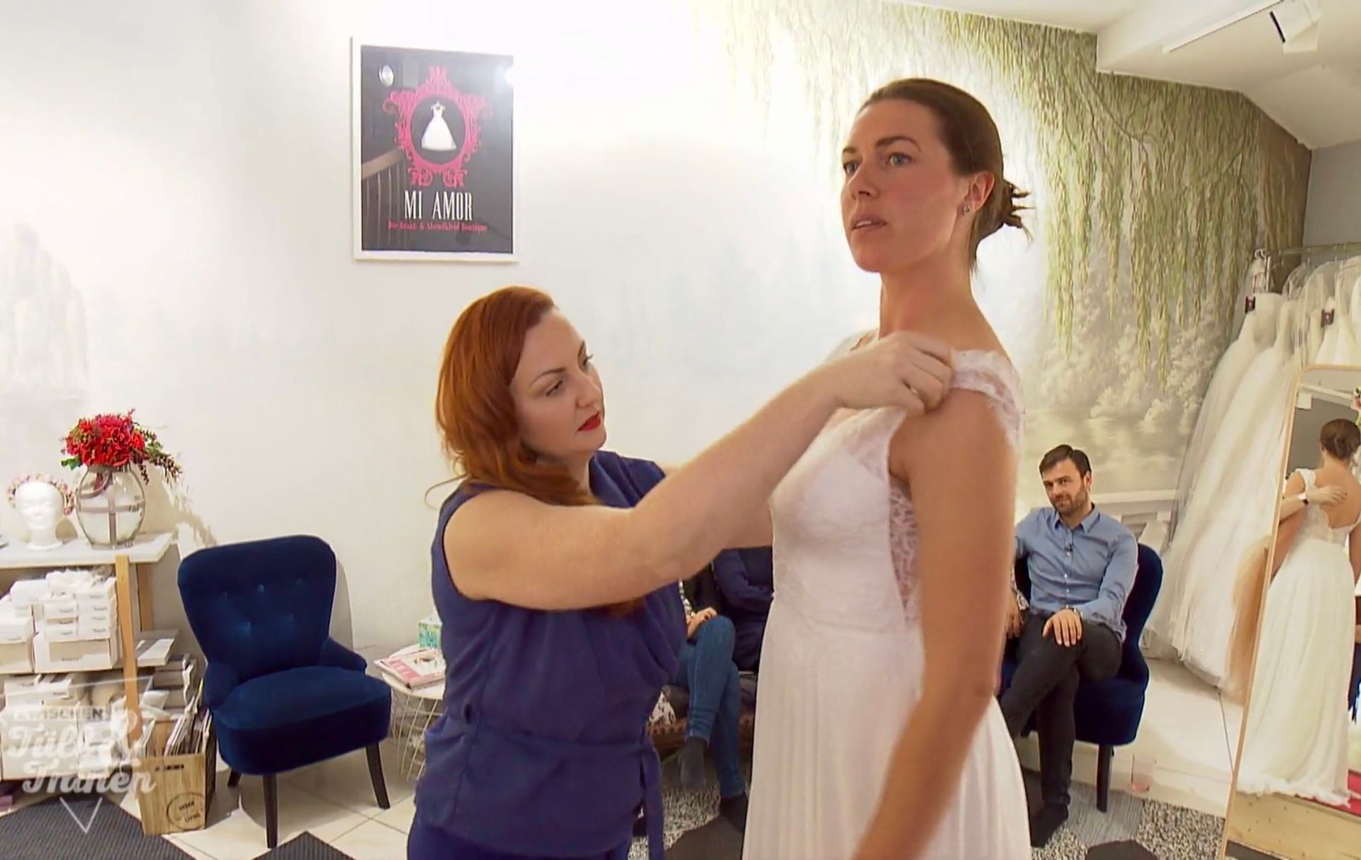 Eine Frau hilft einer anderen Frau beim Anprobieren eines Brautkleides.
