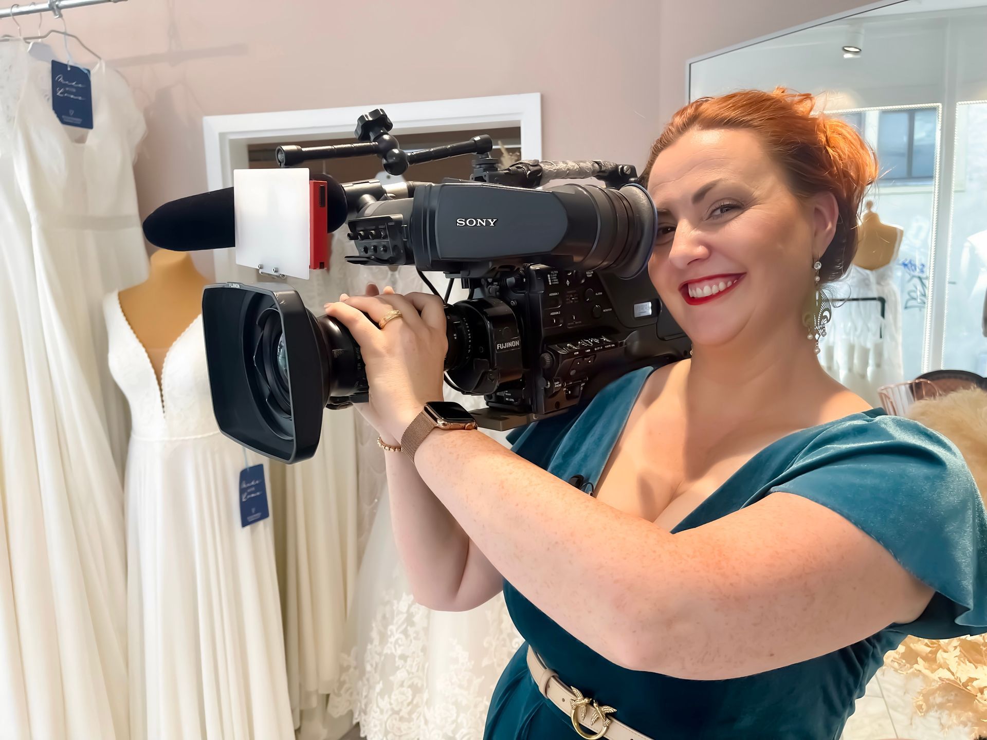 Eine Frau in einem blauen Kleid hält eine Sony-Kamera