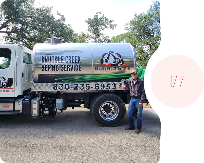 Silver septic-service tanker truck parked outdoors; worker stands beside it.