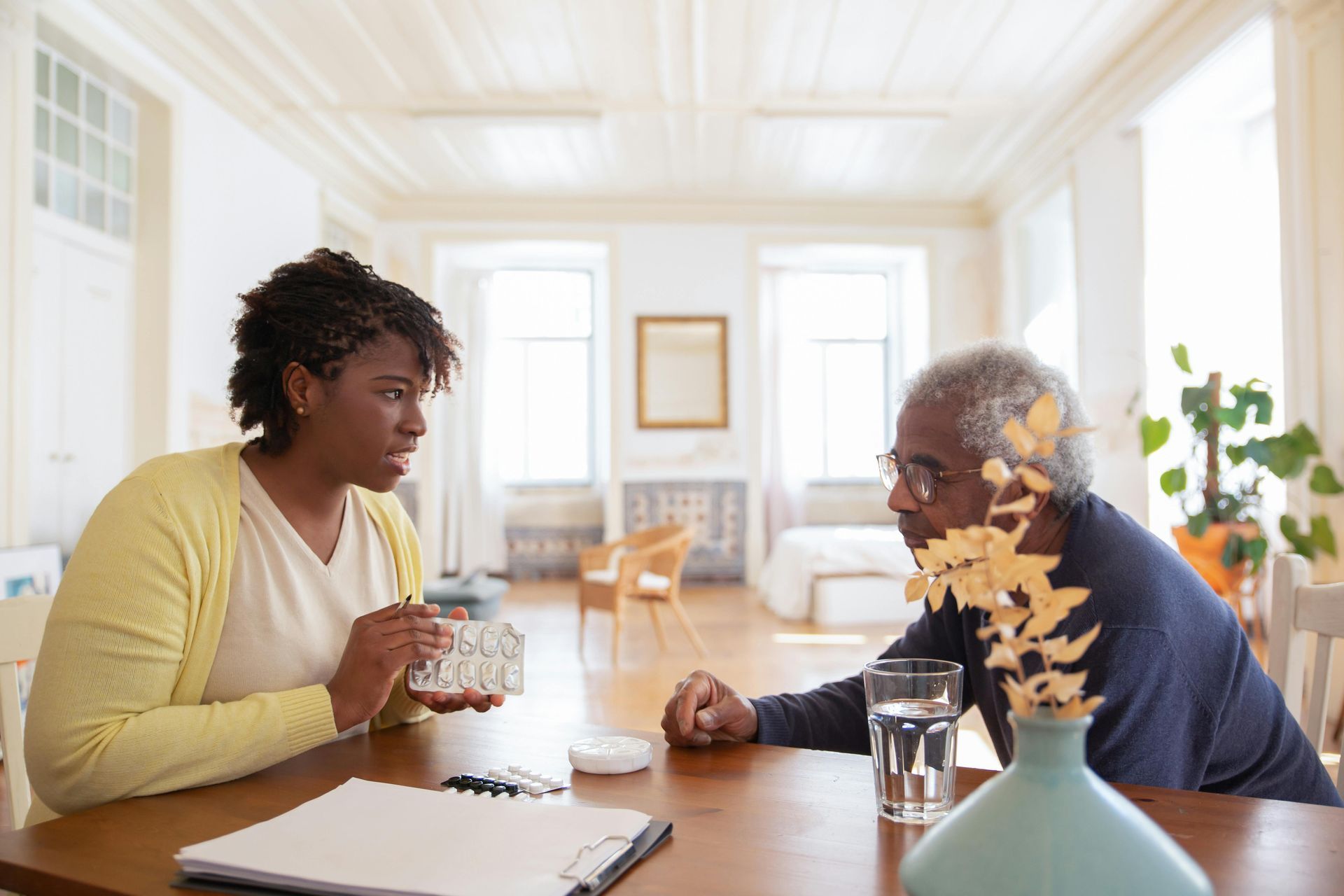 A woman is sitting at a table talking to an older man.