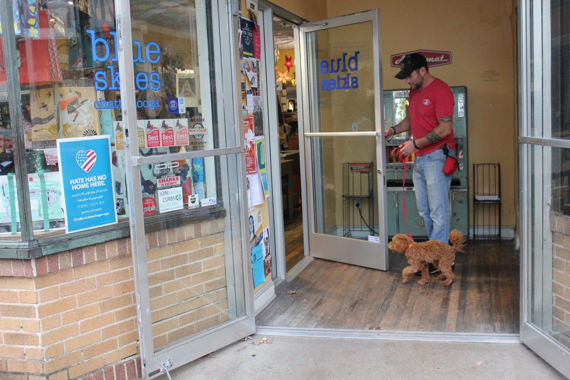 Person with a dog entering a store through open glass doors