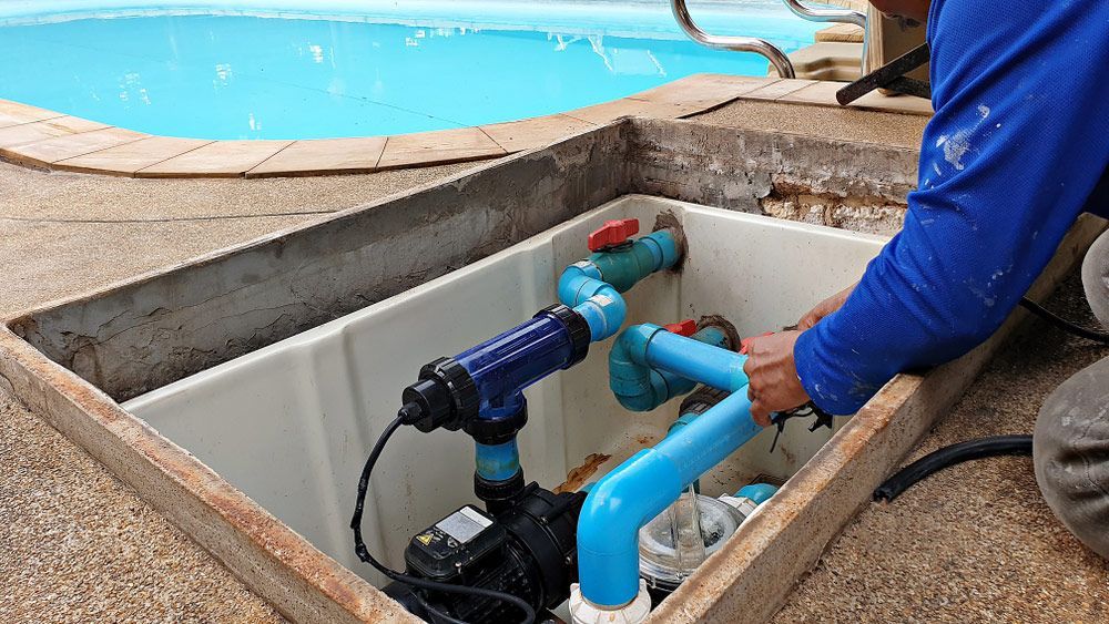 Man is working on a swimming pool pump — Pool Cleaning in Redlynch, QLD