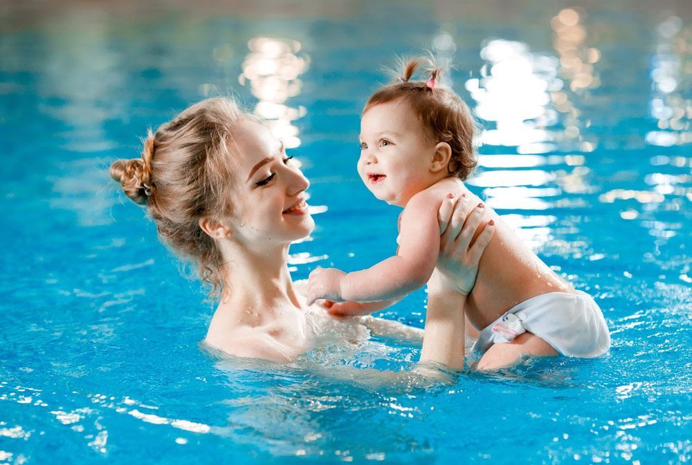 A woman is holding a baby in a swimming pool — Pool Handovers in Kewarra Beach QLD