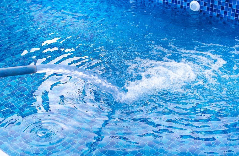 Hose is spraying water into a swimming pool — Pool Cleaning in Cairns, QLD