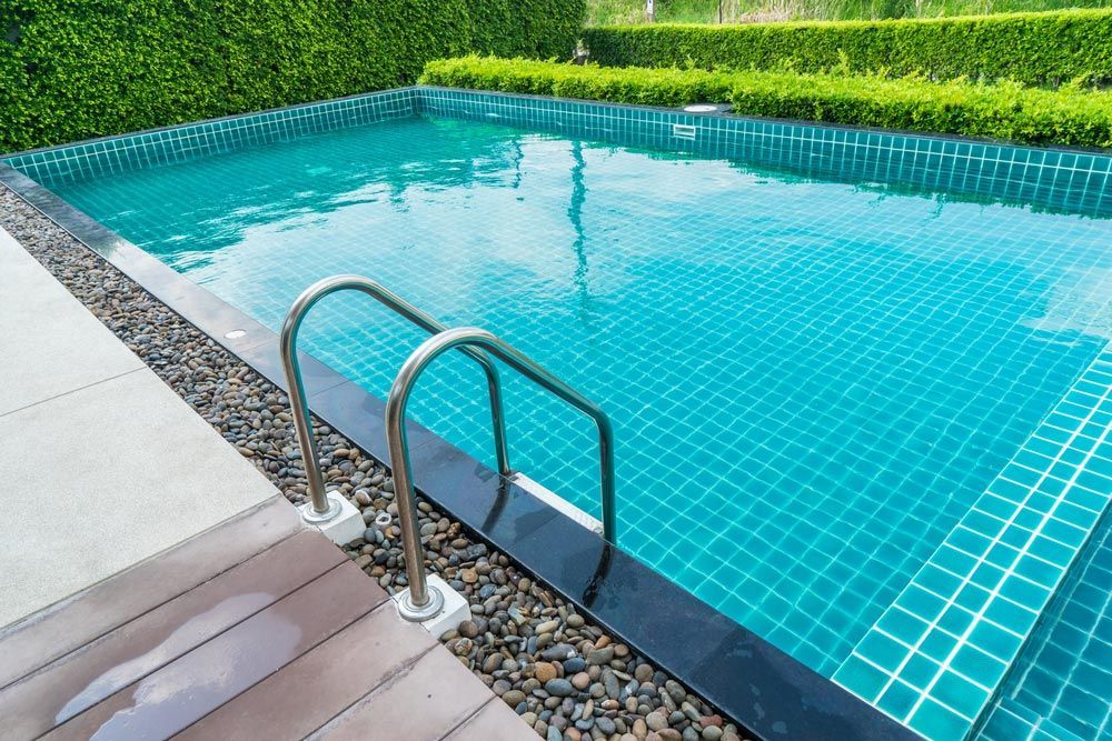 Large swimming pool with stairs with stone around it — Pool Cleaning in Cairns, QLD