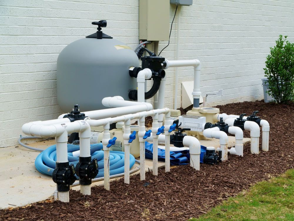 Swimming pool filter is sitting next to a bunch of pipes — Pool Cleaning in Smithfield, QLD