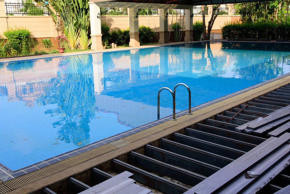 Large swimming pool with a wooden deck — Pool Cleaning in Trinity Beach, QLD