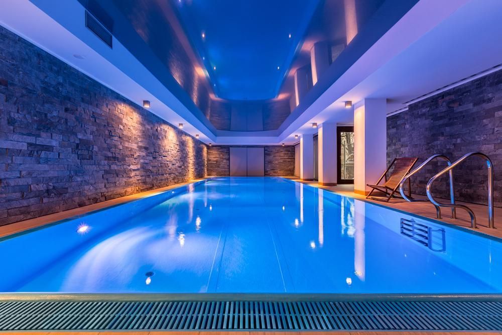 A Large Indoor Swimming Pool Is Lit up At Night — Beaches Pool Supplies in Kewarra Beach, QLD