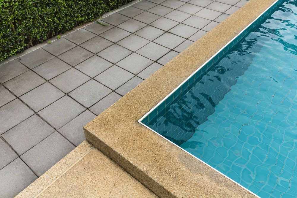 Swimming pool with a tiled walkway surrounding it — Pool Cleaning in Palm Cove, QLD