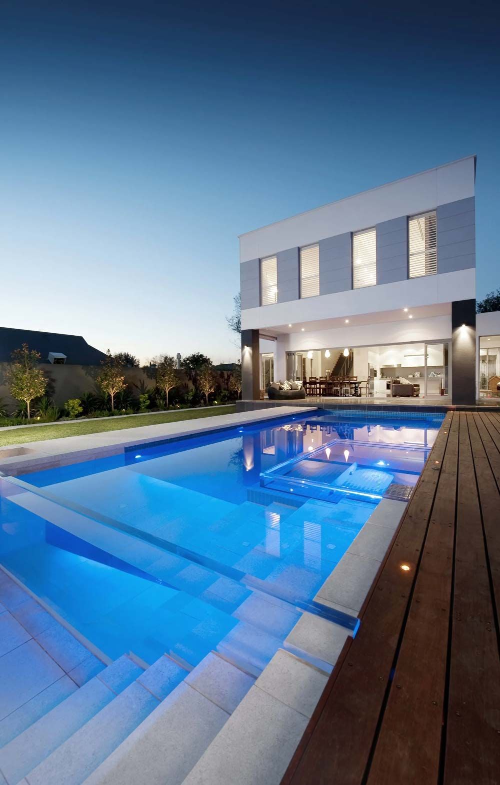 A large swimming pool in front of a house at night — Pool Equipment Installation in Kewarra Beach QLD
