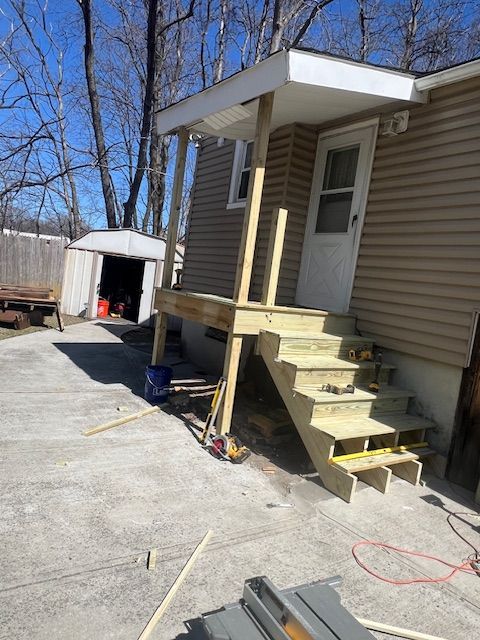 Wooden porch and stairs being built next to a house with a white door.