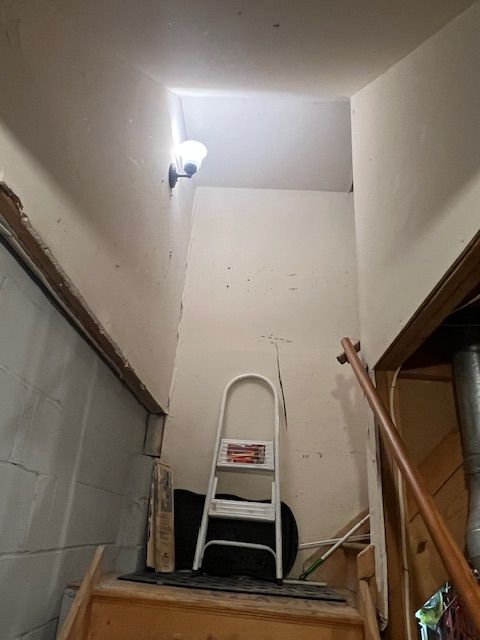 Stairwell with white walls, a step ladder, and a light fixture.