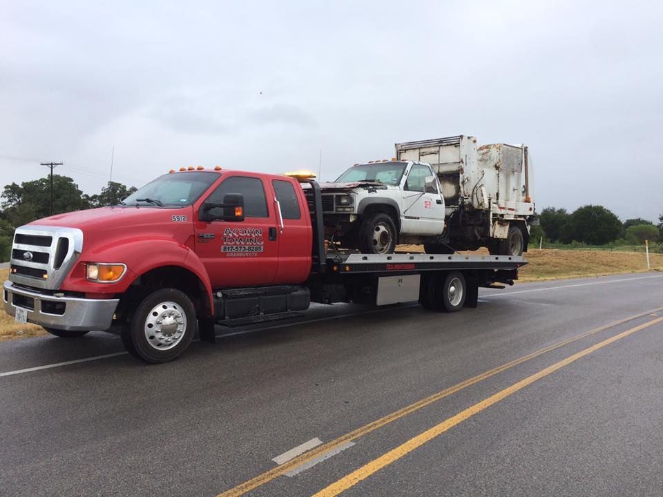 A red tow truck is towing a white truck