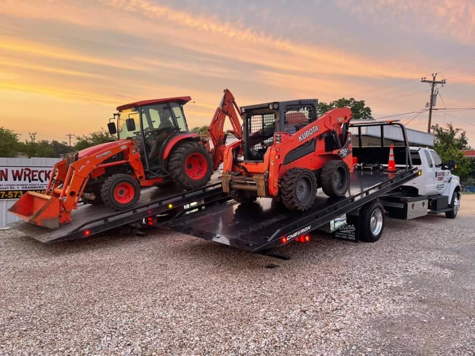 Two tractors are being towed by a tow truck.