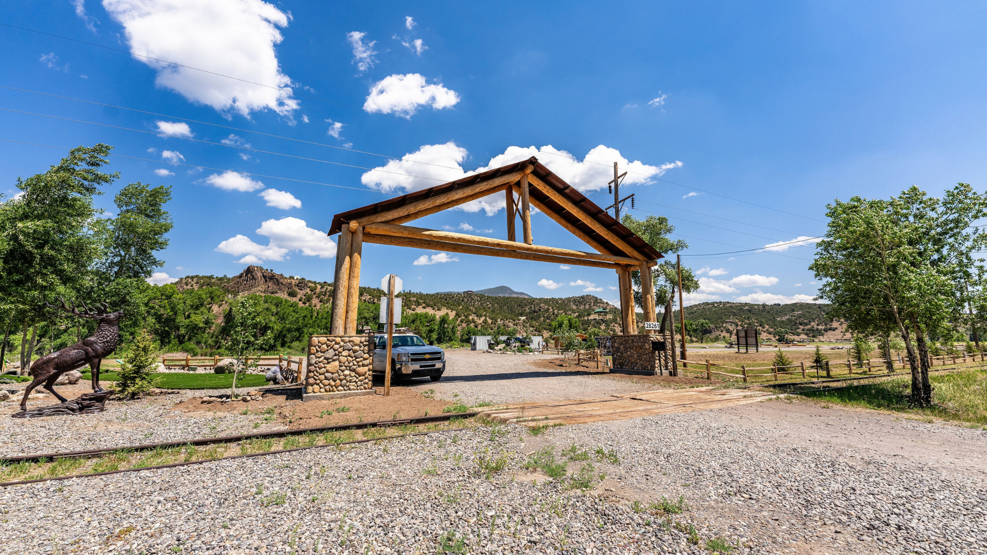 Wooden pavilion in a gravel yard with trees and hills under a blue sky at Rio Grande RV Resort
