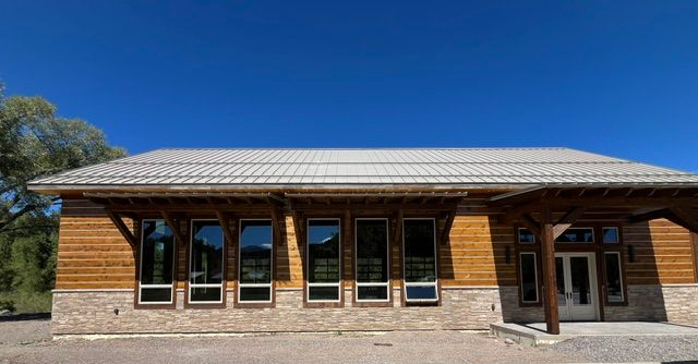 Single-story wooden building with a corrugated metal roof under a clear blue sky