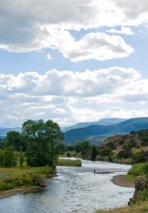 River winding through a green valley with mountains and cloudy sky