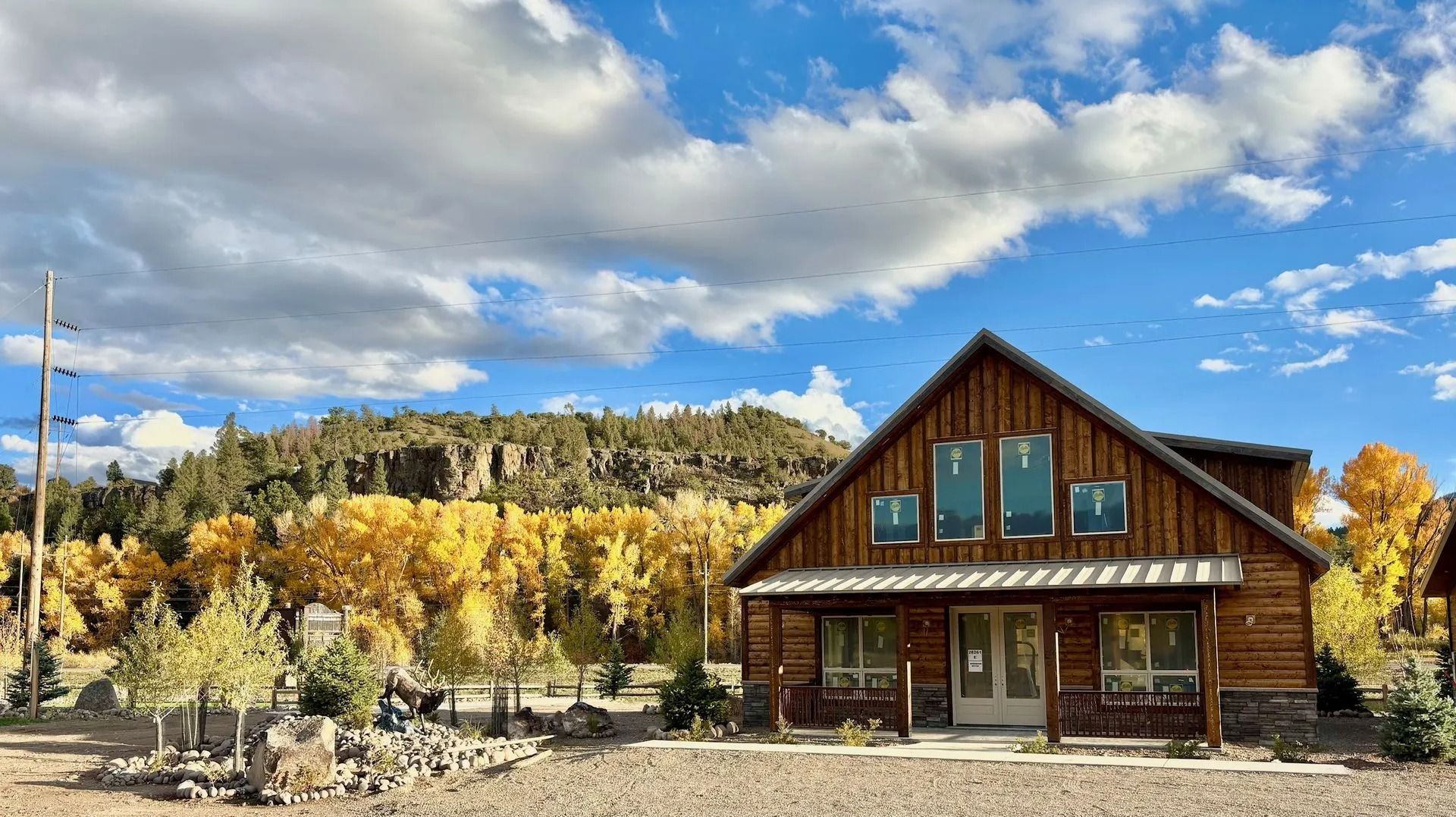 Rustic cabin with blue doors and autumn trees under a partly cloudy sky