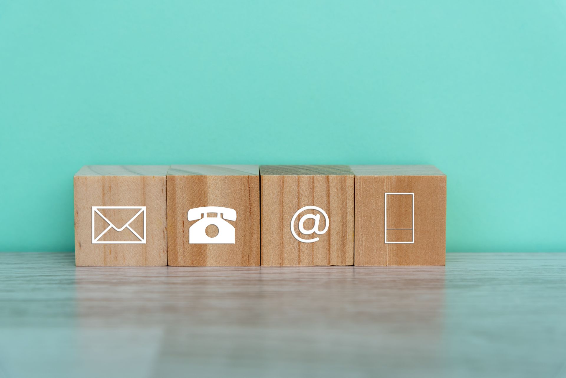 A wooden block with a telephone , email , and phone icon on it. A wooden block with a telephone , email , and phone icon on it.