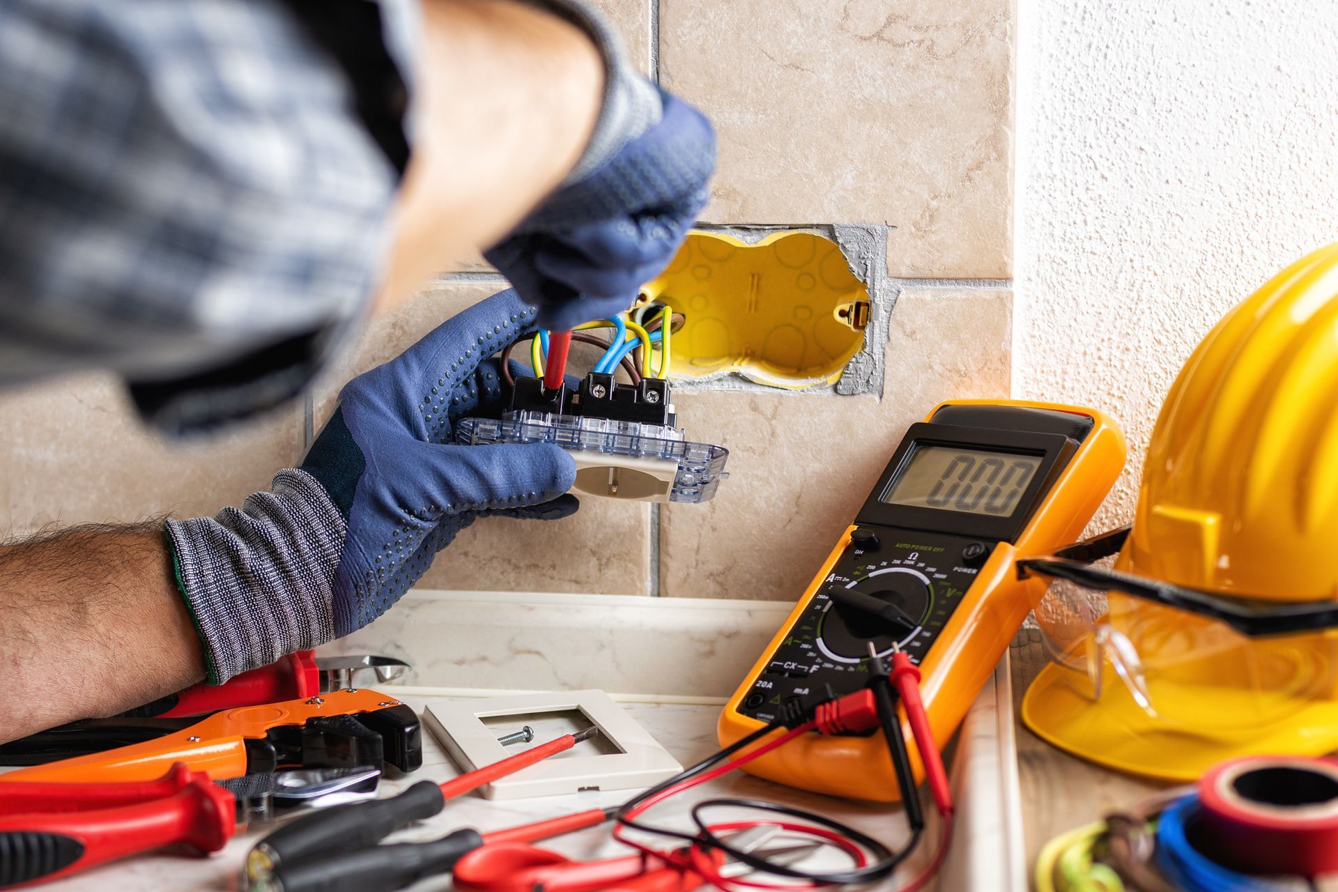 An electrician is working on an electrical outlet with a multimeter. An electrician is working on an electrical outlet with a multimeter.