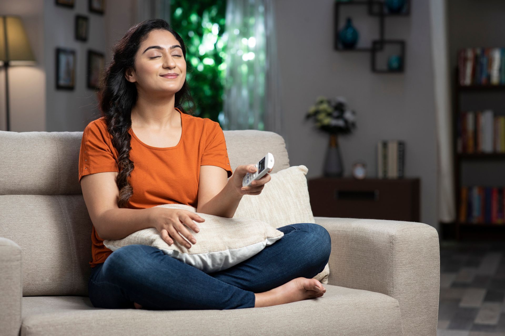A woman is sitting on a couch holding a remote control.
