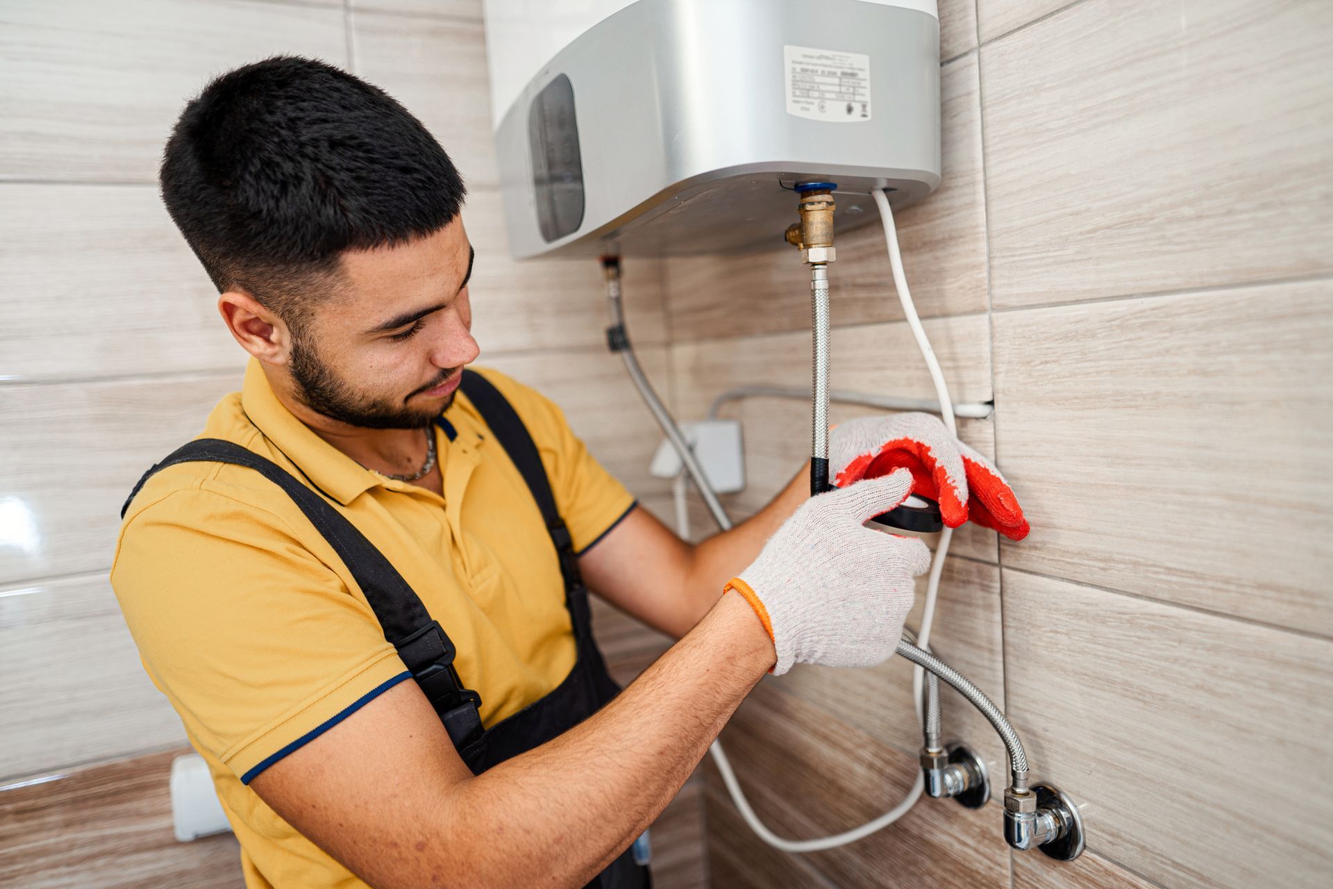 A man is fixing a water heater in a bathroom.