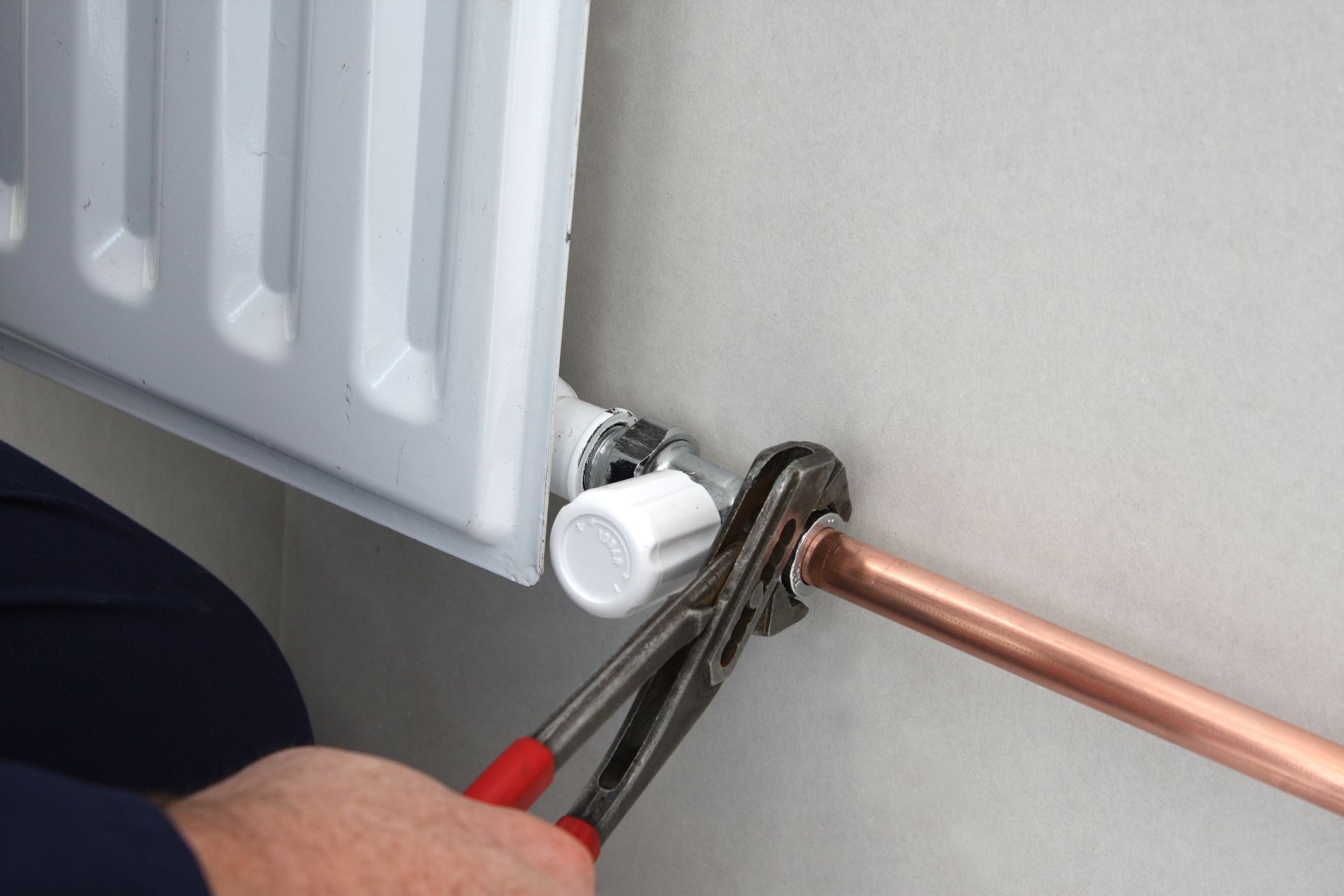 A person is fixing a radiator with a pair of pliers. A person is fixing a radiator with a pair of pliers.
