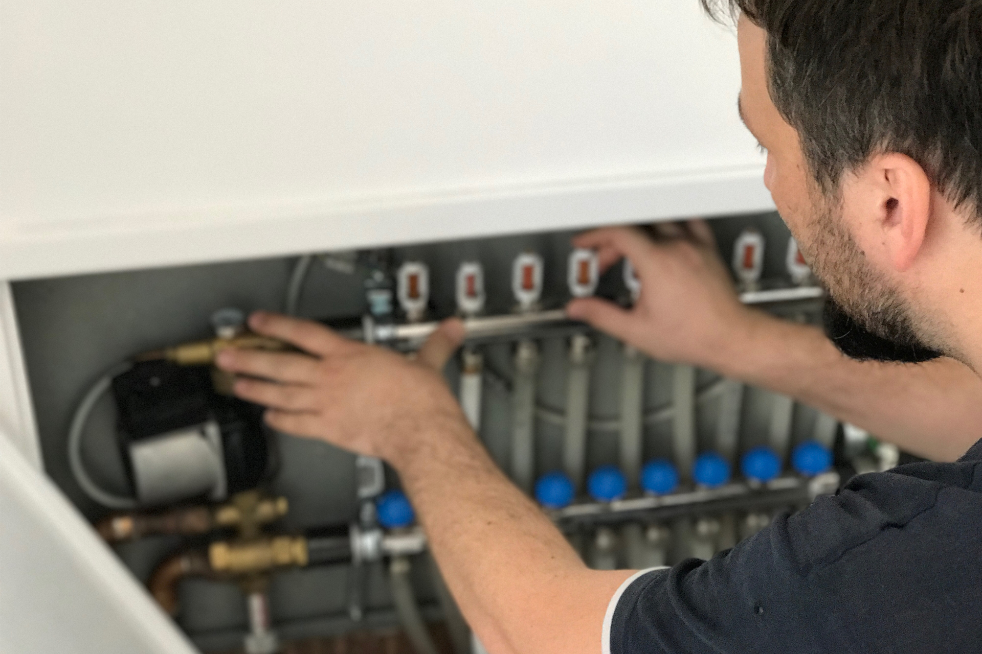 A man is working on a heating system in a cabinet. A man is working on a heating system in a cabinet.