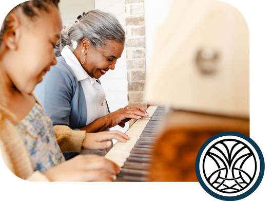 Grandmother and grandchild playing piano together, smiling.