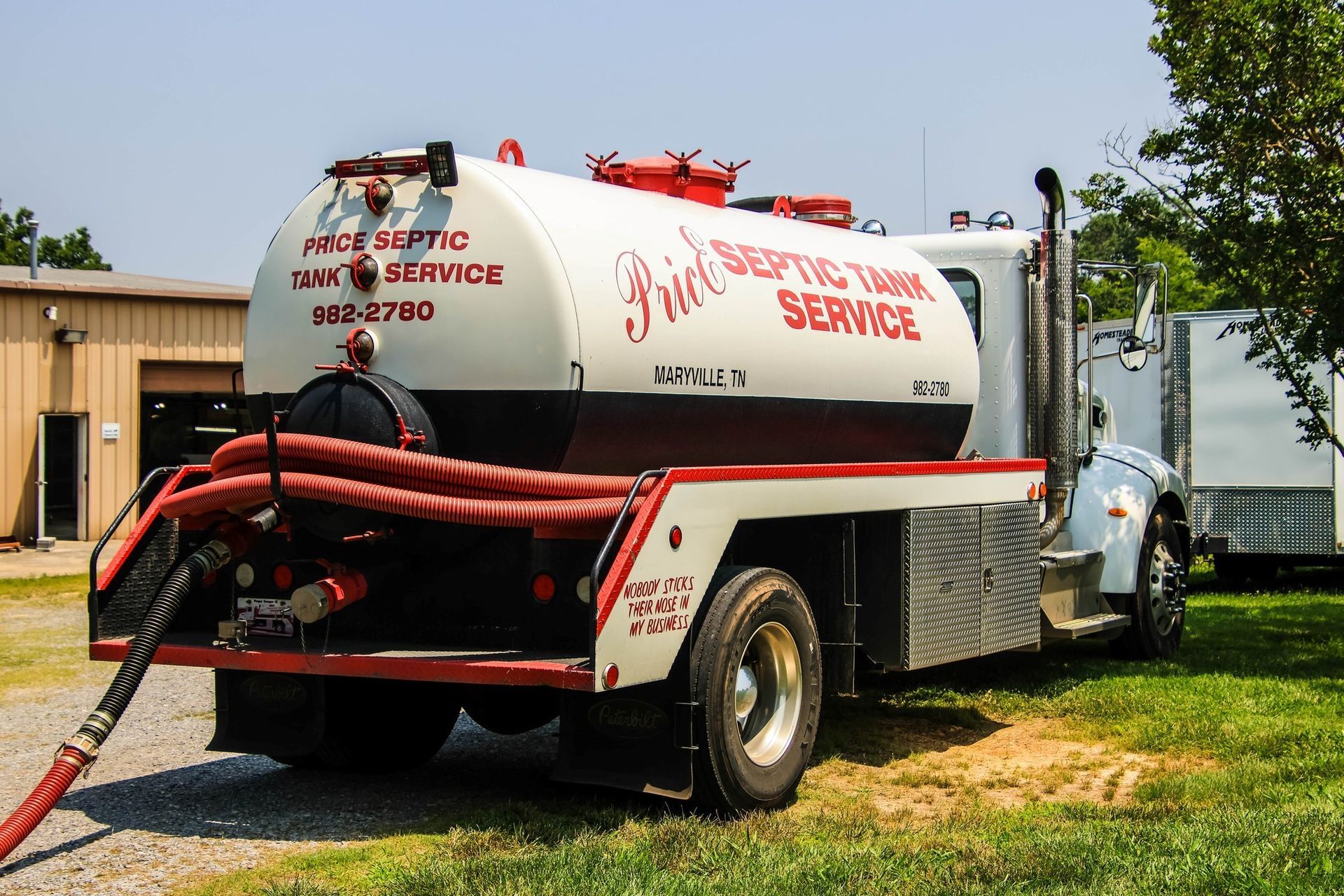 A yellow vacuum truck is parked on the side of the road in front of a building.