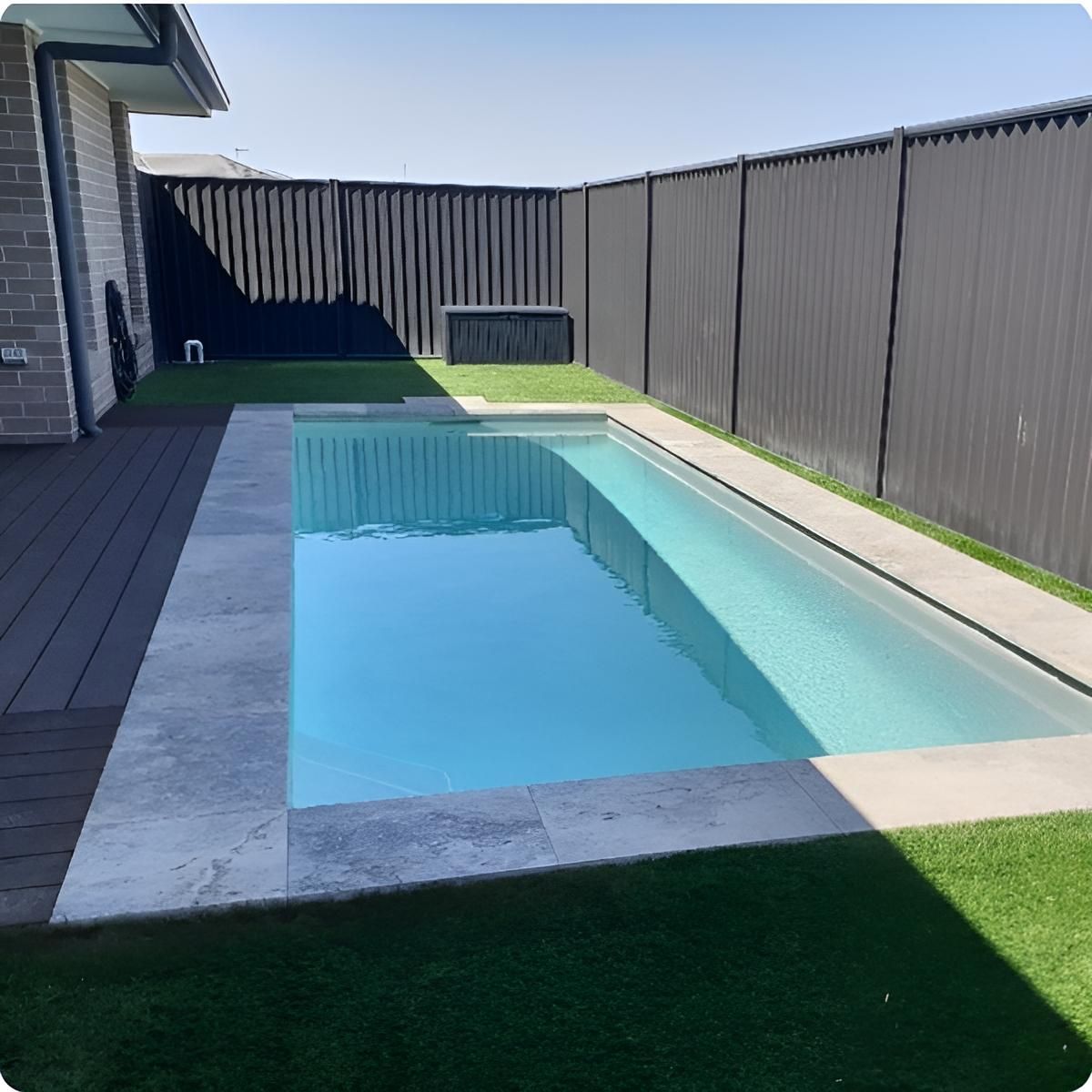 A Swimming Pool In A Backyard With A Black Fence — Ballina Pool Shop In Ballina, NSW