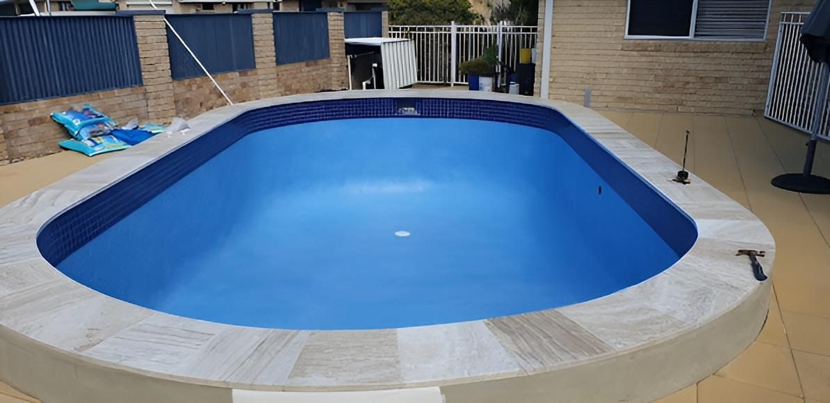 A Large Blue Swimming Pool Is Sitting On A Patio Next To A House — Ballina Pool Shop In Ballina, NSW